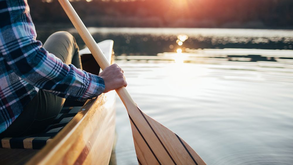 woman paddling canoe in lake